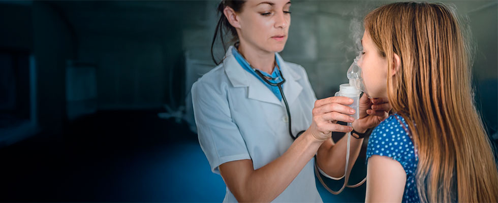 Una profesional de la salud asistiendo a una niña en la administración de un tratamiento respiratorio con nebulizador.